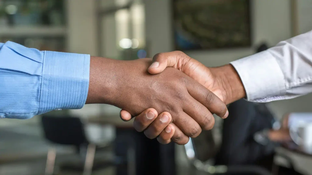 Close-up view of corporate business partners exchanging a firm handshake in a bright office environment to finalize a new deal