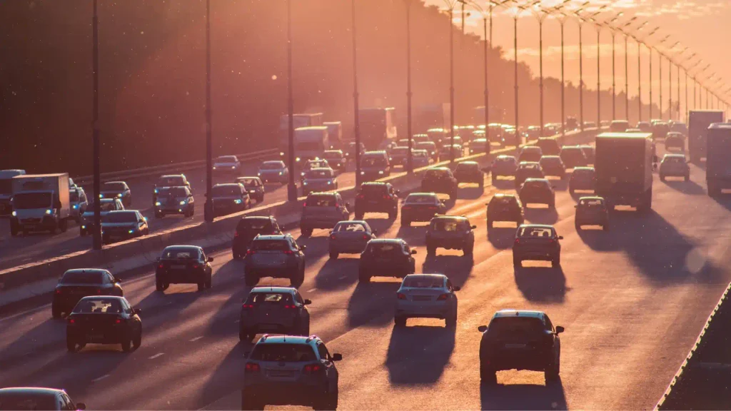 Heavy traffic of cars and trucks driving on a multi-lane highway bathed in the warm glow of a scenic setting evening sun
