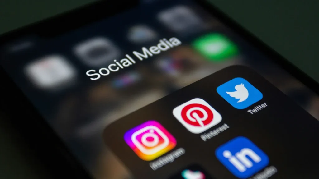 Close-up of a smartphone screen showing a folder of popular social media app icons like Instagram, Pinterest, and Twitter